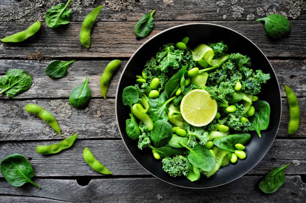 Salade verte végétalienne avec haricots edamame, chou frisé, pousses d'épinards et citron vert.