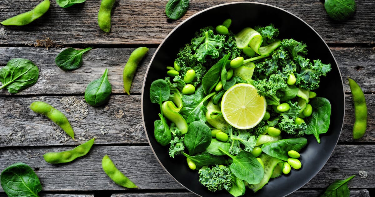 Salade verte végétalienne avec haricots edamame, chou frisé, pousses d'épinards et citron vert.