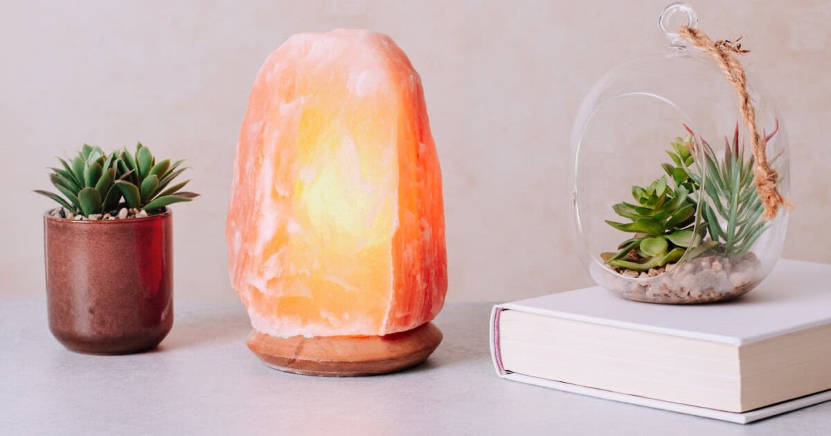 Lampe au sel de l'Himalaya sur table avec plantes et livre, contrôle du stress, décoration apaisante.