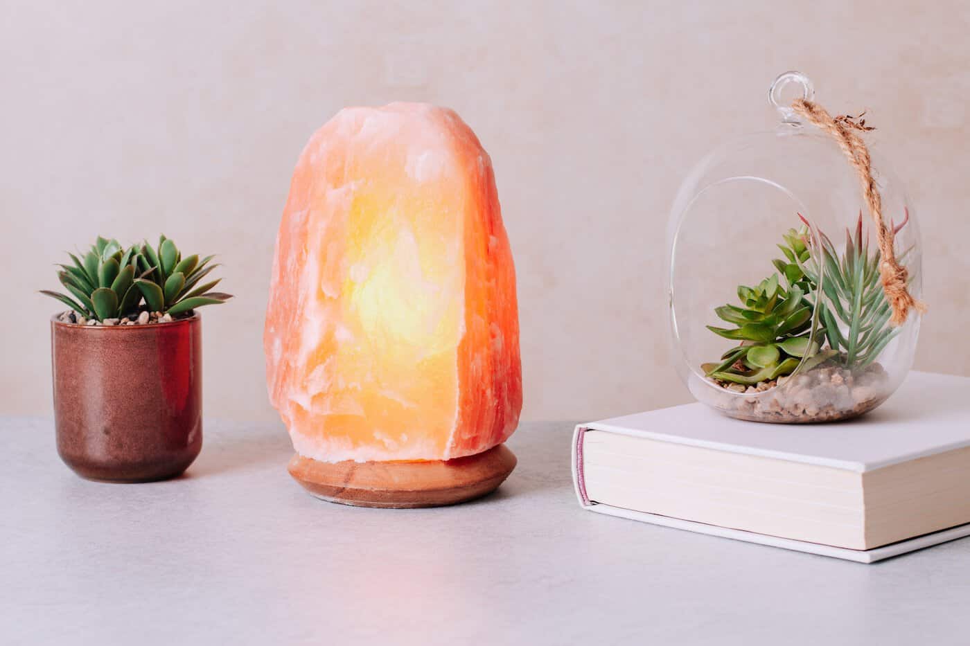 Lampe au sel de l'Himalaya sur table avec plantes et livre, contrôle du stress, décoration apaisante.