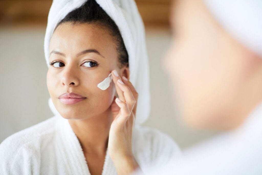 Femme métisse appliquant la crème pour le visage