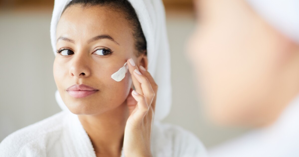 Femme métisse appliquant la crème pour le visage