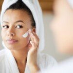 Femme métisse appliquant la crème pour le visage