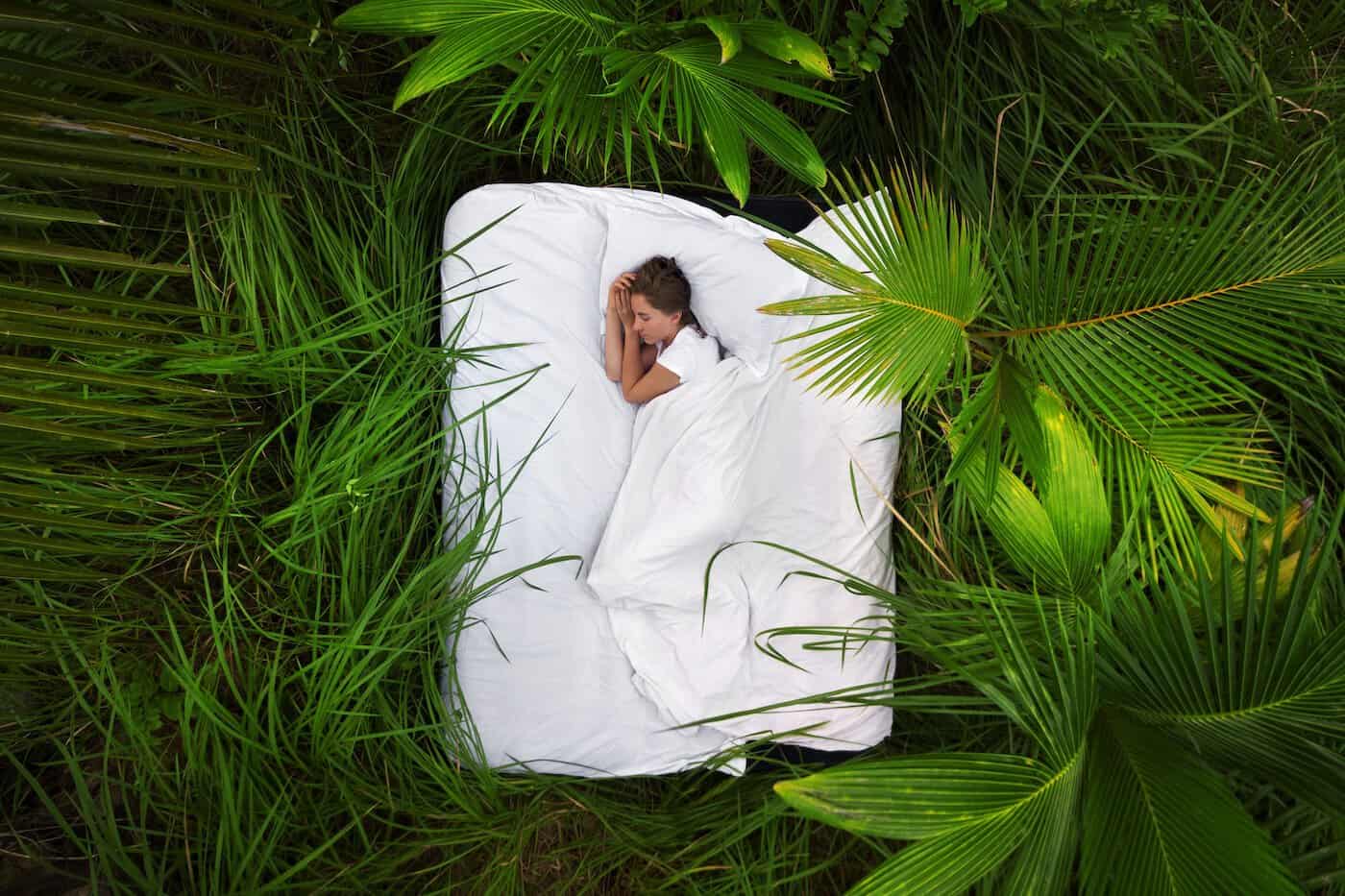Une femme endormie dans une forêt de jungle profonde se trouve sur un matelas gonflable, vue d'en haut