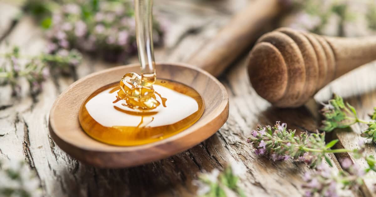 Miel aux herbes versé dans la cuillère en bois.