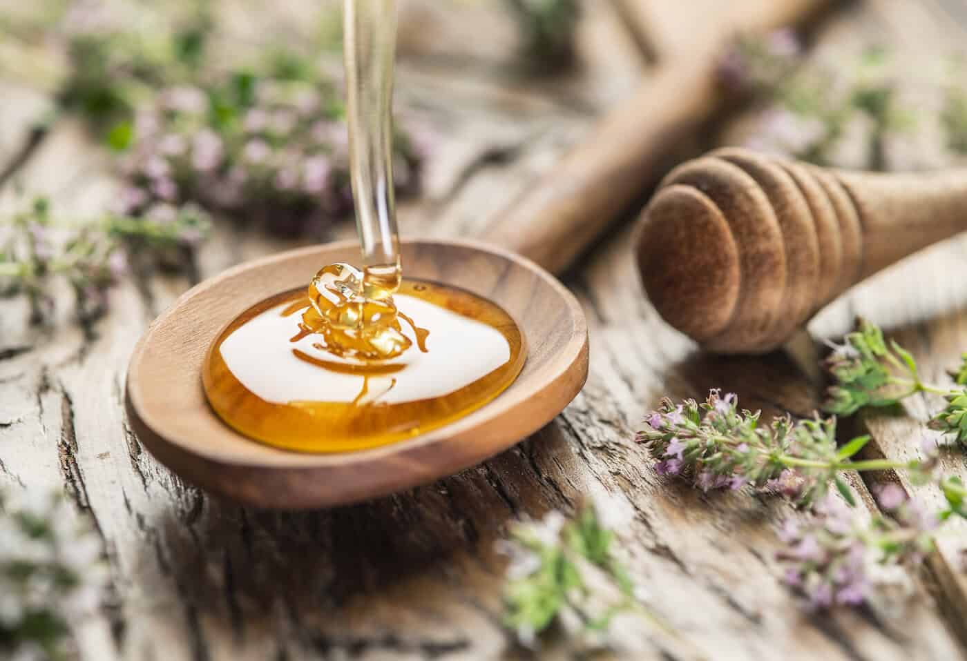 Miel aux herbes versé dans la cuillère en bois.