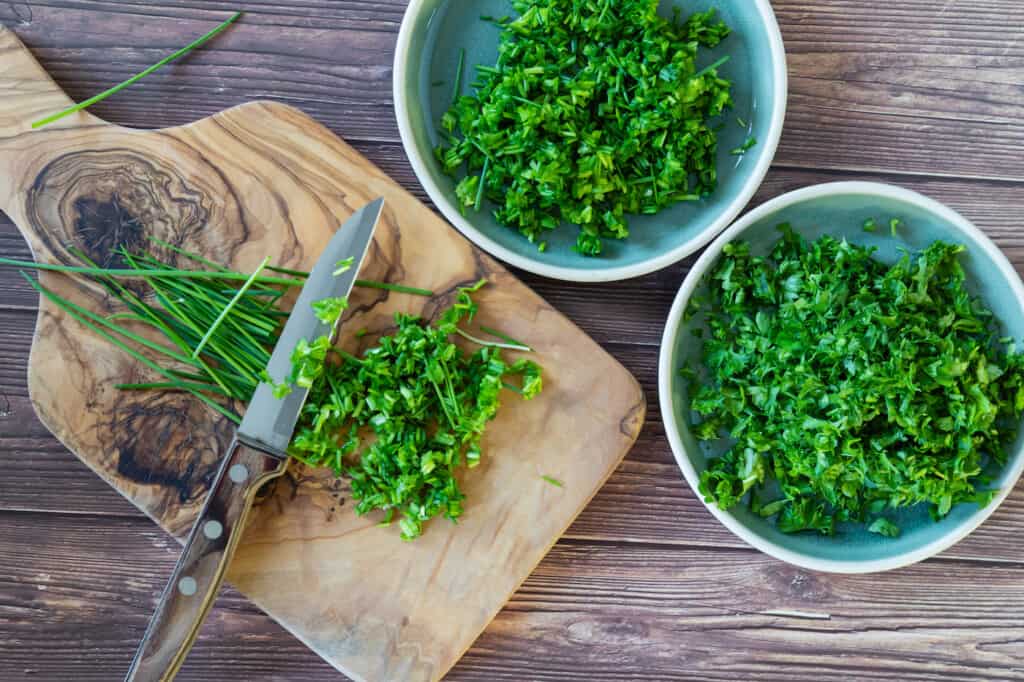 Persil épicé frais et haché et herbes de ciboulette sur planche à découper, vue de dessus