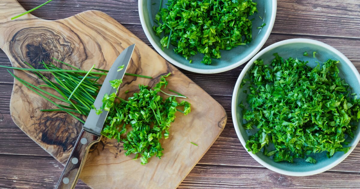 Persil épicé frais et haché et herbes de ciboulette sur planche à découper, vue de dessus