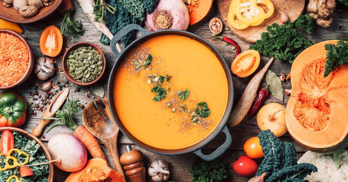 Soupe à la citrouille avec ingrédients de cuisine végétariens, cuillères en bois, ustensiles de cuisine sur fond en bois. Vue de dessus.