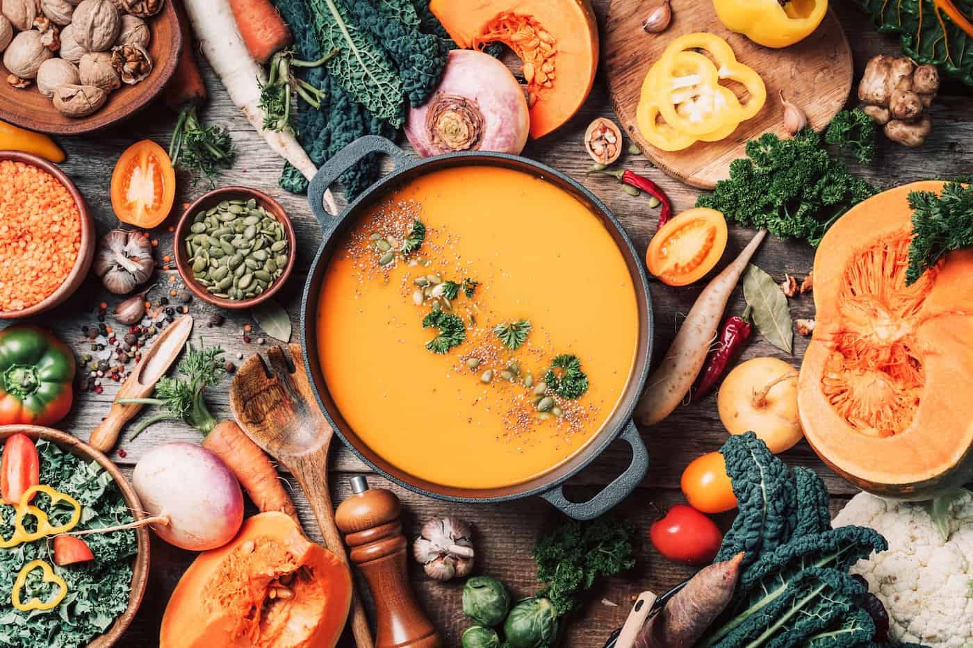 Soupe à la citrouille avec ingrédients de cuisine végétariens, cuillères en bois, ustensiles de cuisine sur fond en bois. Vue de dessus.