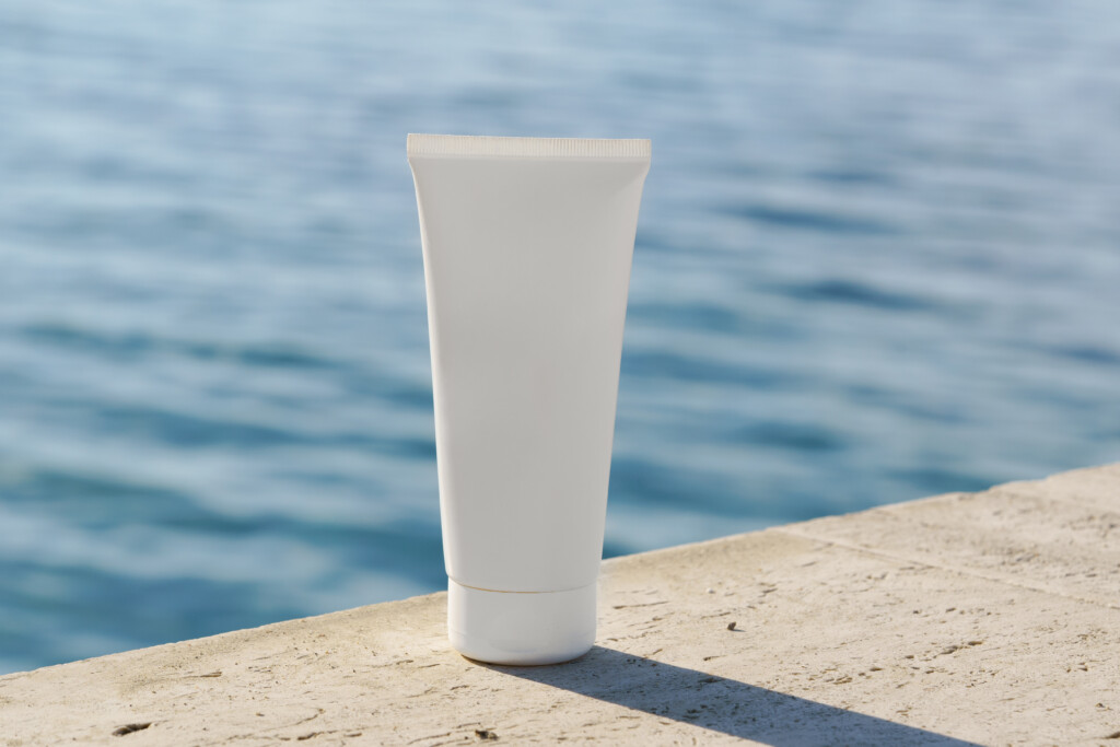 Tube cosmétique placé sur des rochers avec la mer en arrière-plan.