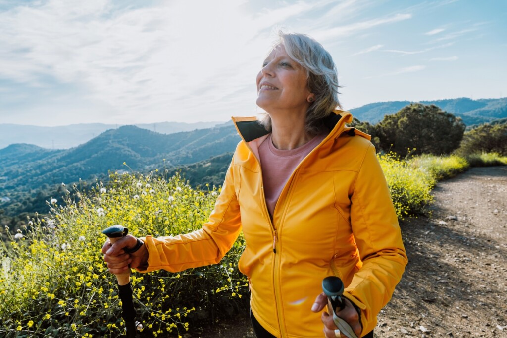 Femme âgée active faisant de la randonnée sur un sentier extérieur à l'aide de bâtons de randonnée