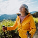 Femme âgée active faisant de la randonnée sur un sentier extérieur à l'aide de bâtons de randonnée